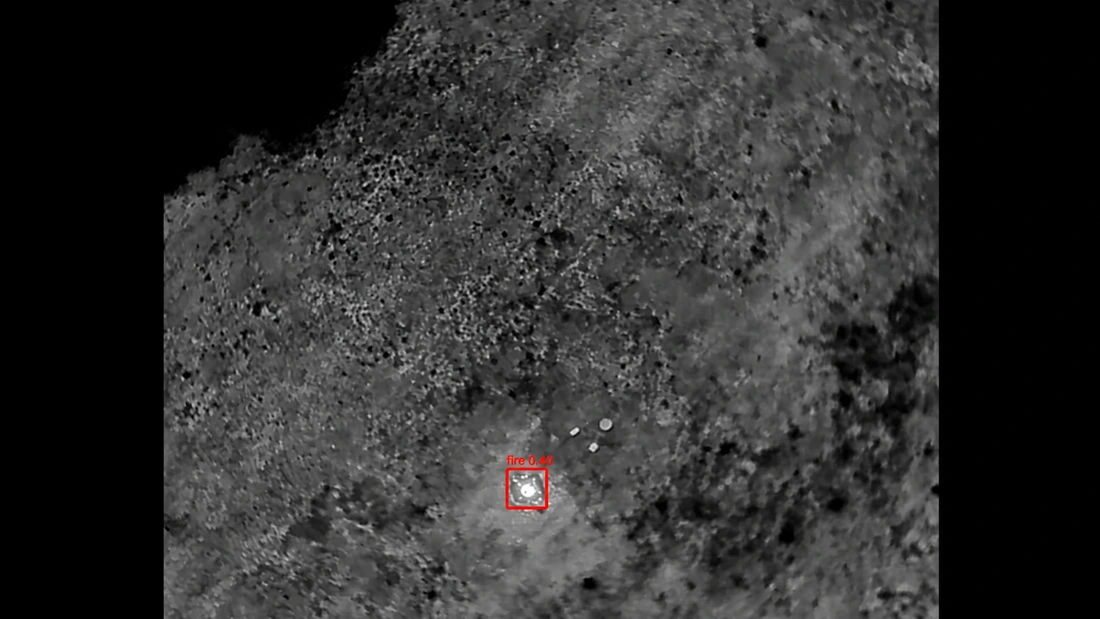 Greyscale aerial view with a bright area marked by a red detection box